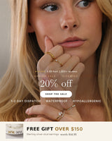 Close-up of stacked dainty gold rings with pear-cut cubic zirconia and pearl stones on a model's hand. Spring Sale — 20% off sitewide, free gift over $150.