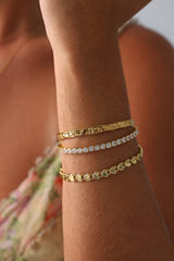 Triple gold and silver bracelet stack featuring hammered bangle, CZ tennis bracelet, and heart-link chain—elegant holiday gift for her