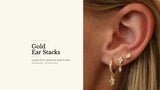 Gold ear stack — pavé huggie hoop with a marquise drop, bezel-set trio dangle and marquise stud layered on one ear. 18k gold-plated on 925 sterling silver.