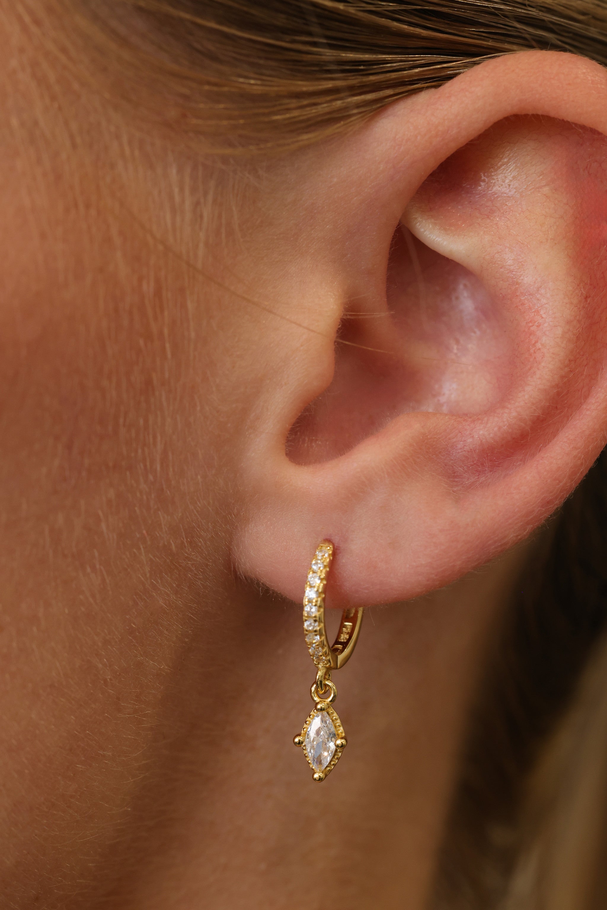 Model wearing the Sara gold marquise drop huggie, angled view