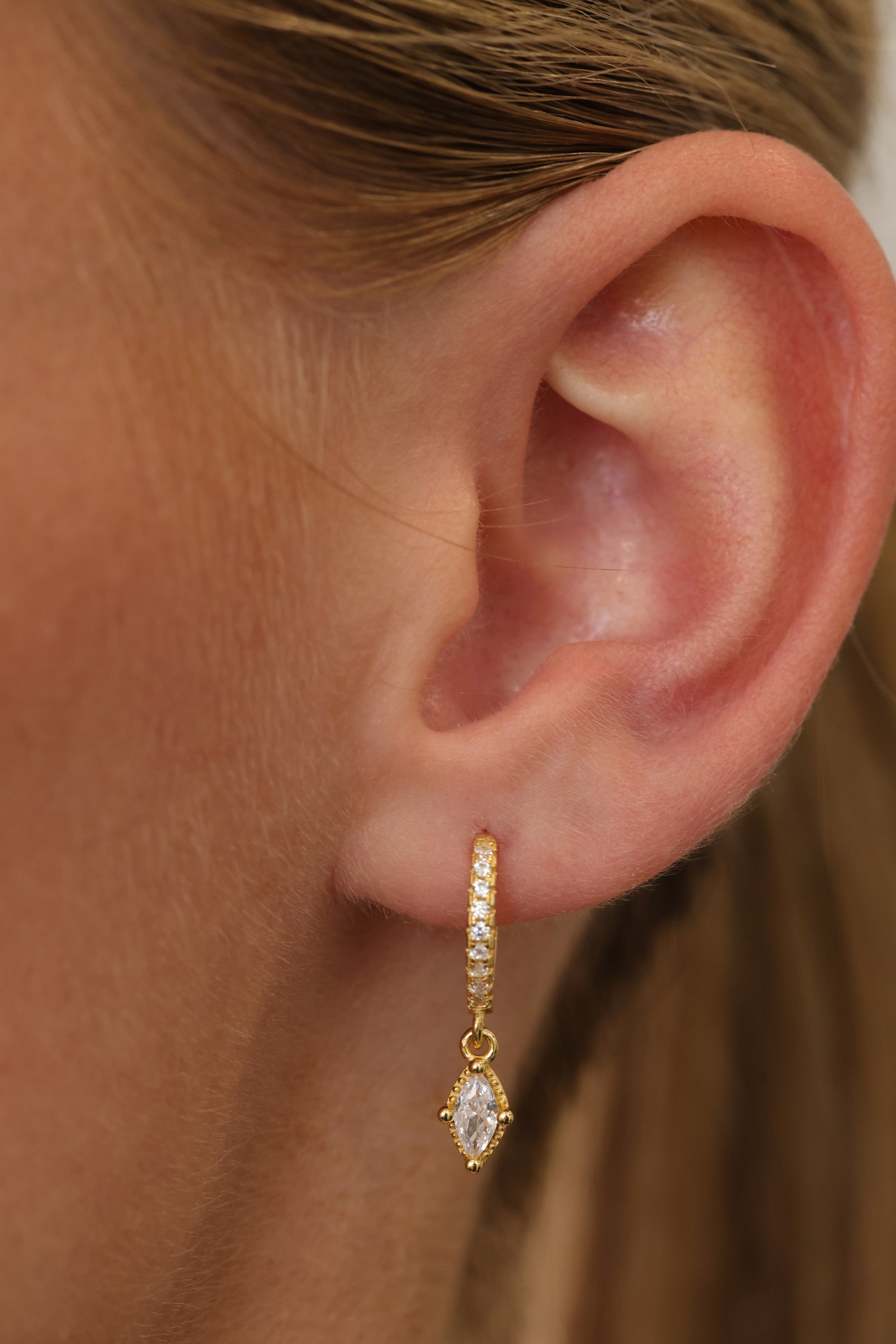 Model wearing the Sara gold marquise drop huggie, side profile