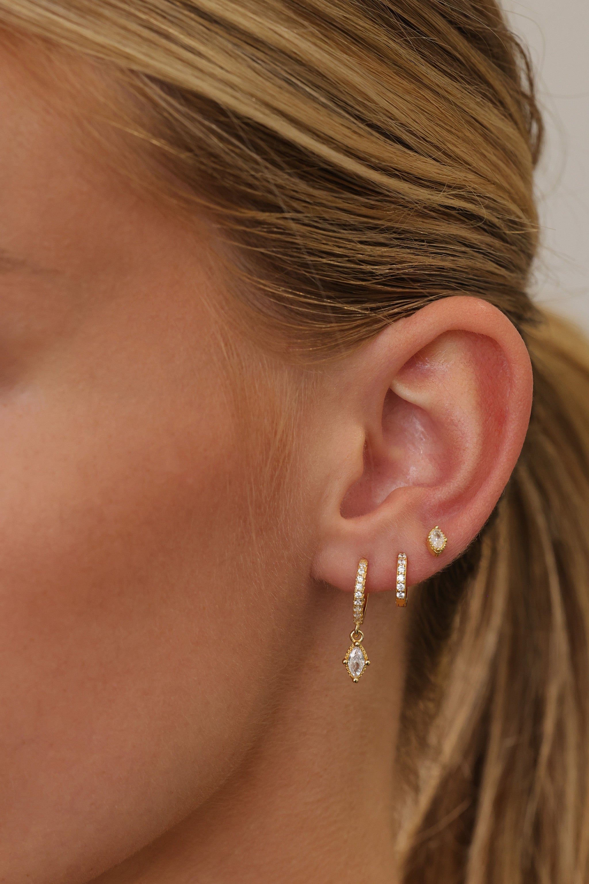 Sara gold ear stack shown wider on the ear — drop huggie, pave huggie and marquise stud
