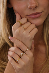 Eloise pear solitaire ring worn in a gold ring stack, close view