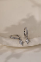 Pair of Sara sterling silver marquise drop huggie earrings on a cream ceramic dish