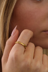 Delphine star eternity band in gold worn on a hand against white eyelet fabric