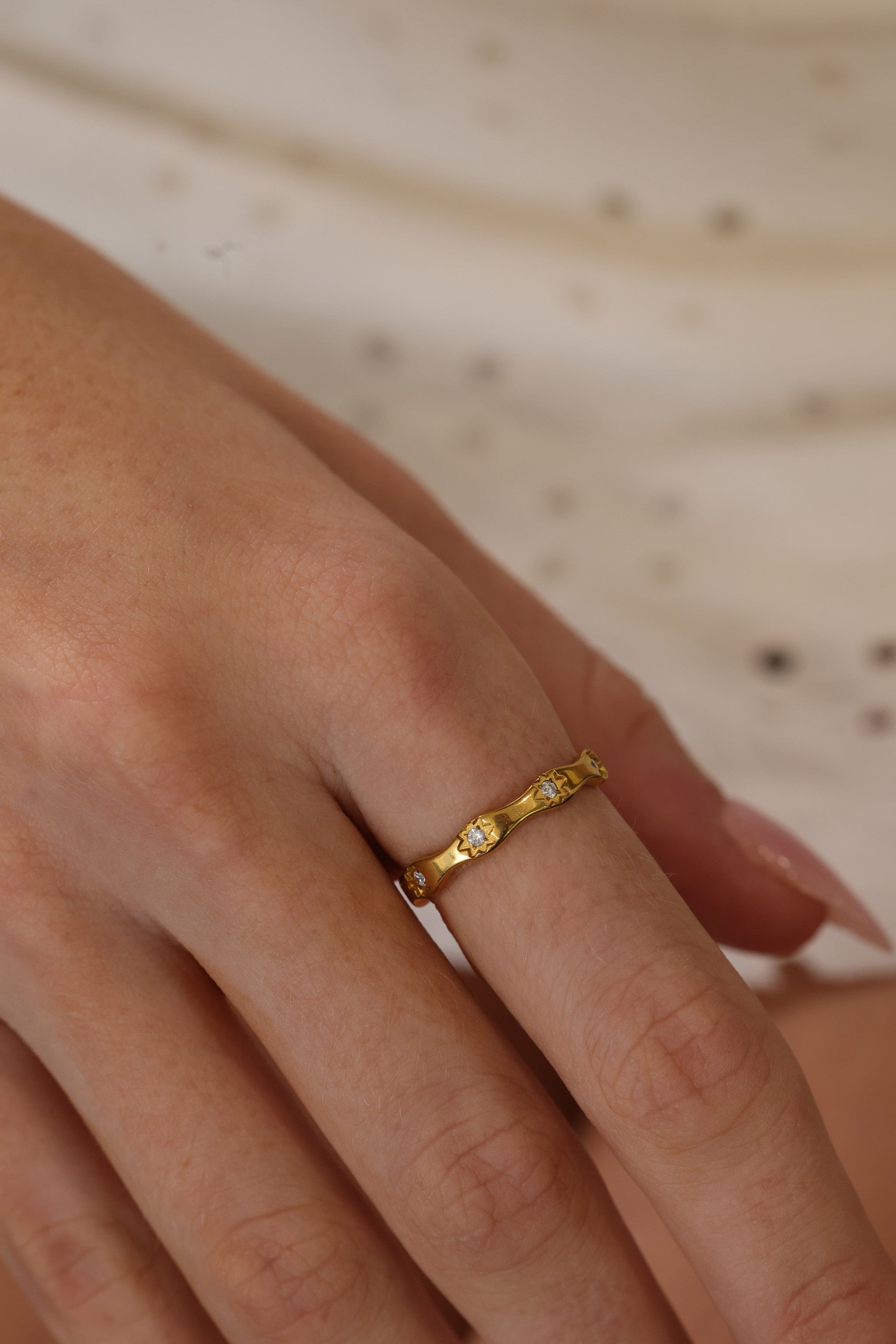 Delphine star eternity band worn on a hand laid flat, gold