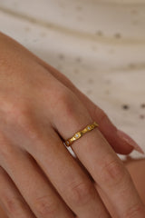 Delphine star eternity band worn on a hand laid flat, gold