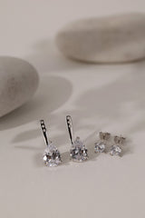 Silver Adamas ear jackets showing the three adjustment holes, beside round studs and white pebbles.