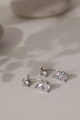Sterling silver Adamas ear jacket earrings standing on cream linen, stud above a pear-cut drop.