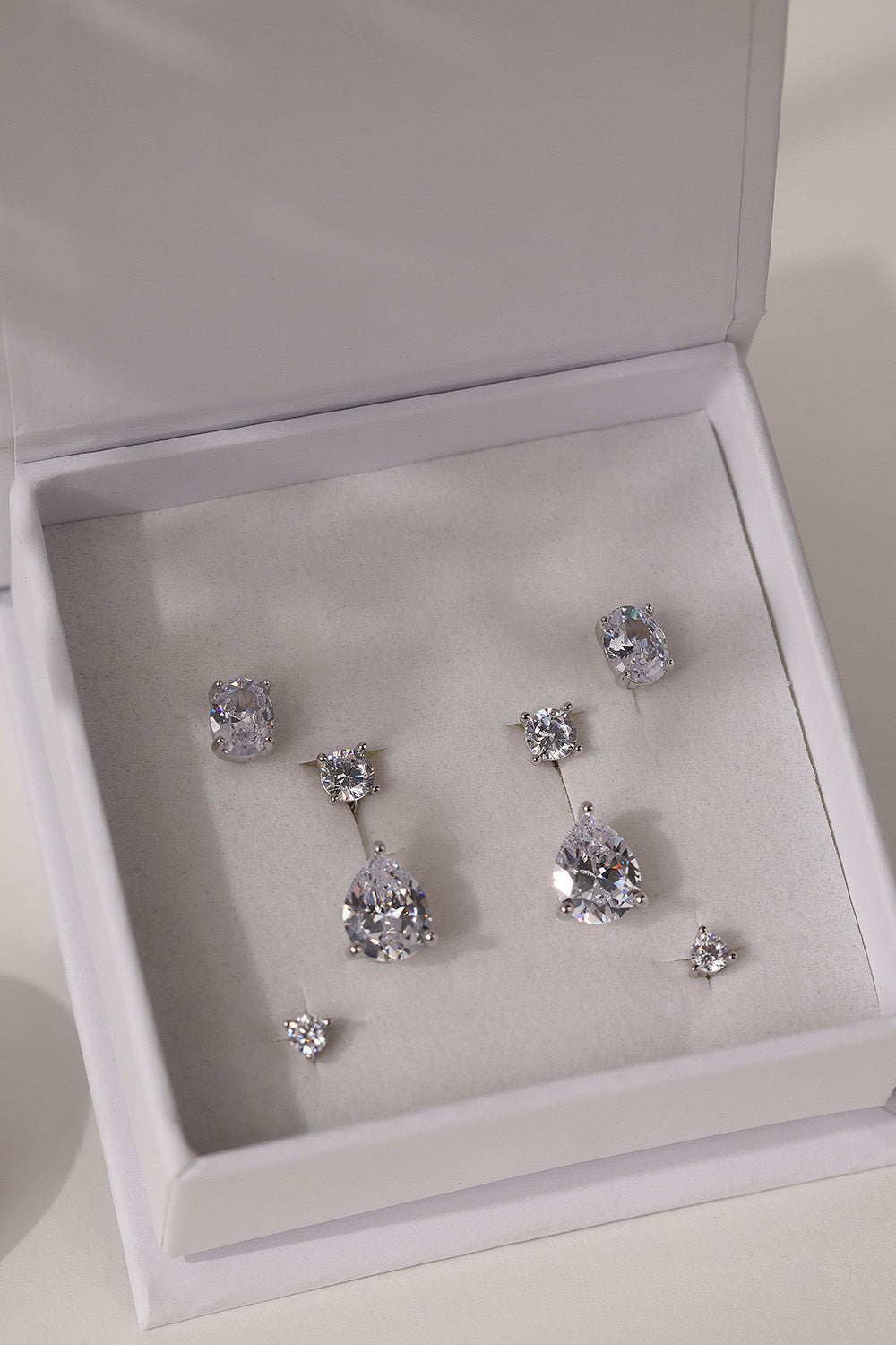 Full silver Adamas set in a white ANETT gift box — oval studs, round studs and pear drop ear jackets.