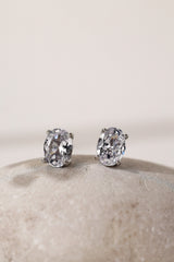 Close-up of silver oval cubic zirconia stud earrings, 8mm by 6mm stones on a pale stone.