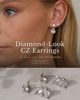 Close-up of a model's ear wearing silver diamond-look CZ pear drop ear jacket earrings with two studs. The Sparkle Edit — 20% off sitewide, Shop the Sparkle Edit.