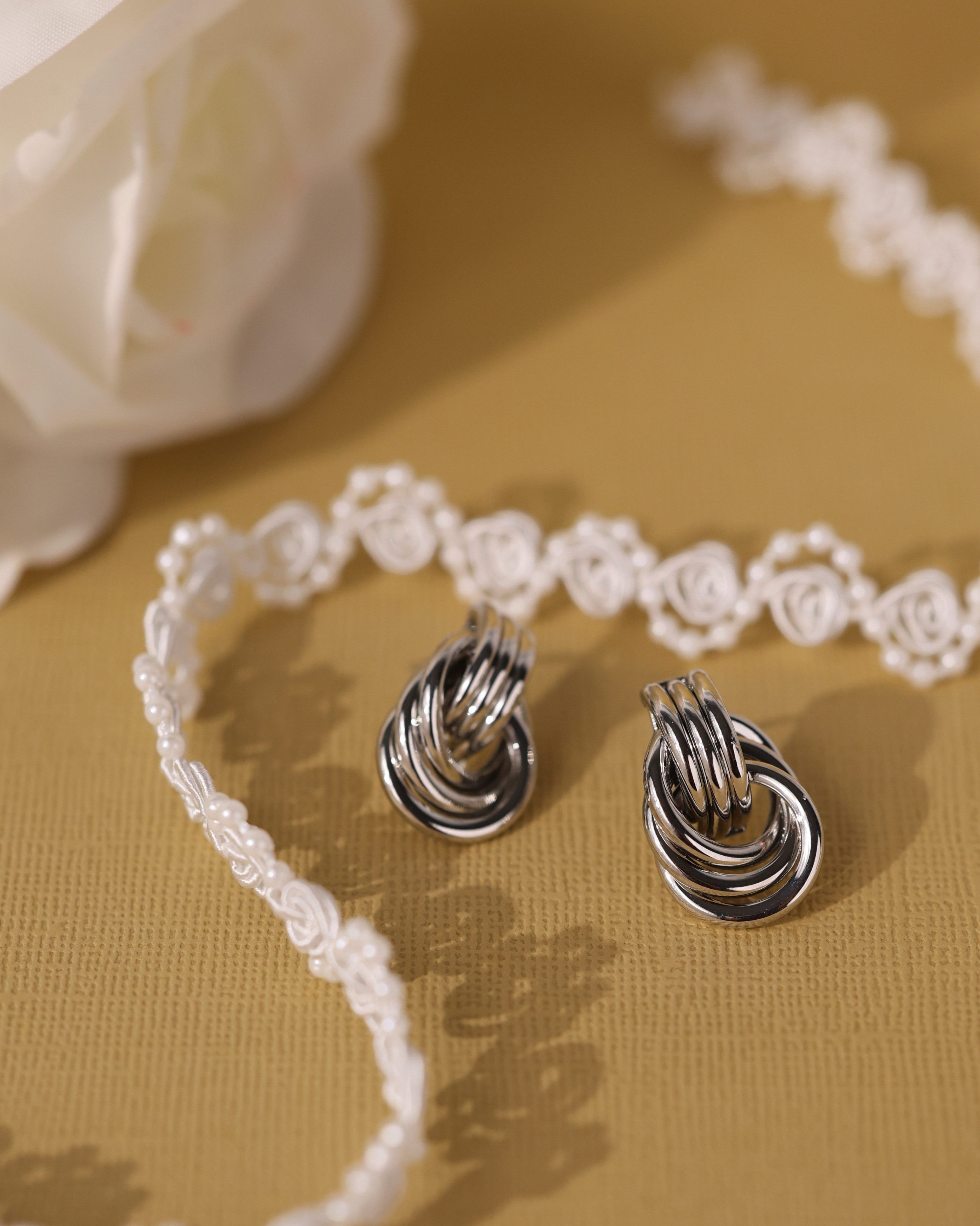 Silver interlocking ring earrings with a polished knot design that reflects light beautifully.