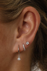 A three‑pair sterling silver earring set featuring a CZ dangle earring, a small cubic zirconia huggie hoop, and a delicate CZ stud. All pieces are rhodium‑plated 925 sterling silver, hypoallergenic, nickel‑free, and displayed together as a coordinated trio.