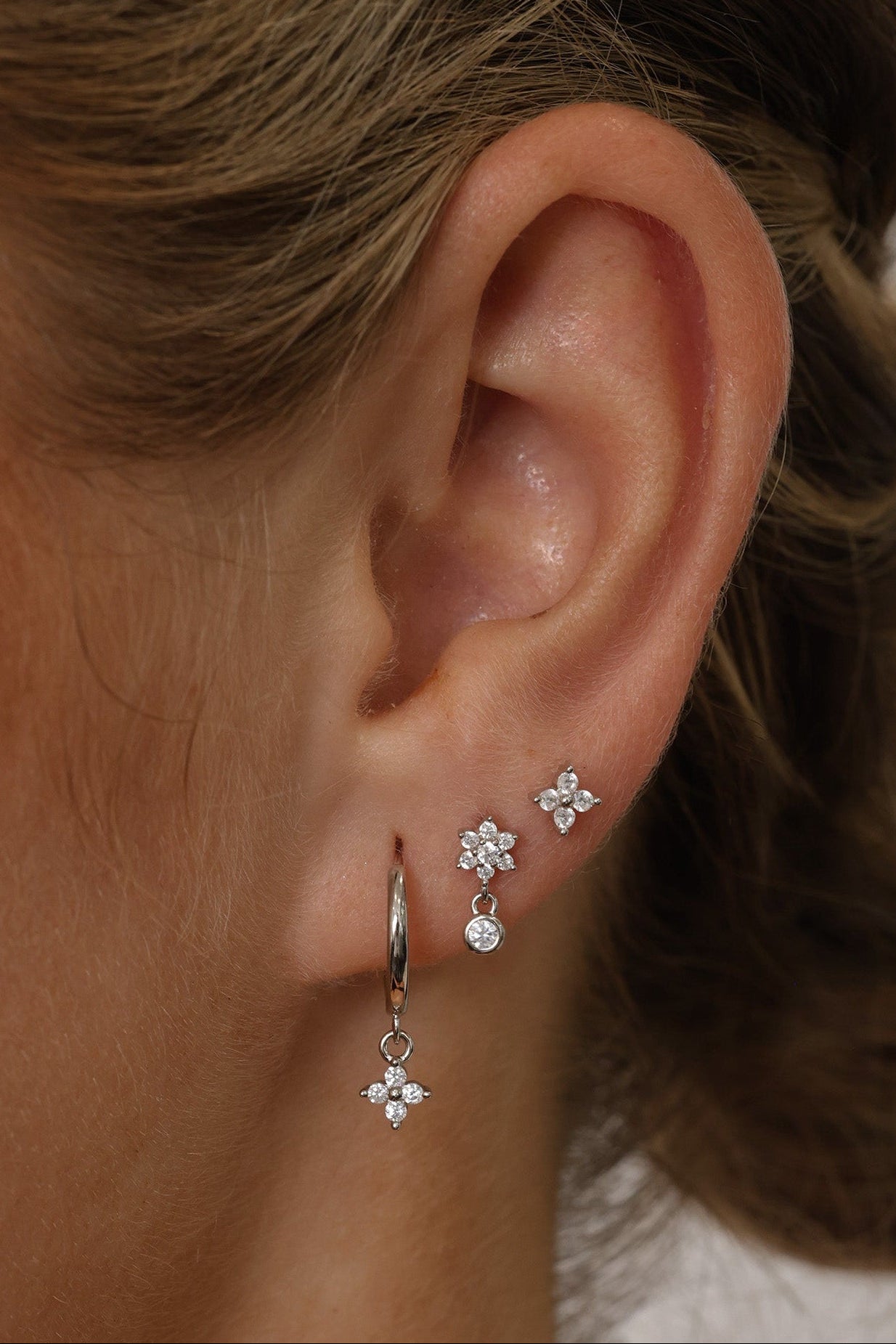 Small silver clover earring set with dangle, snowflake stud, and mini clover stud displayed on a clean background.”