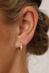Gold‑plated sterling silver opal huggie hoop earrings with shimmering opal inlays, shown for a soft, elegant, iridescent look.