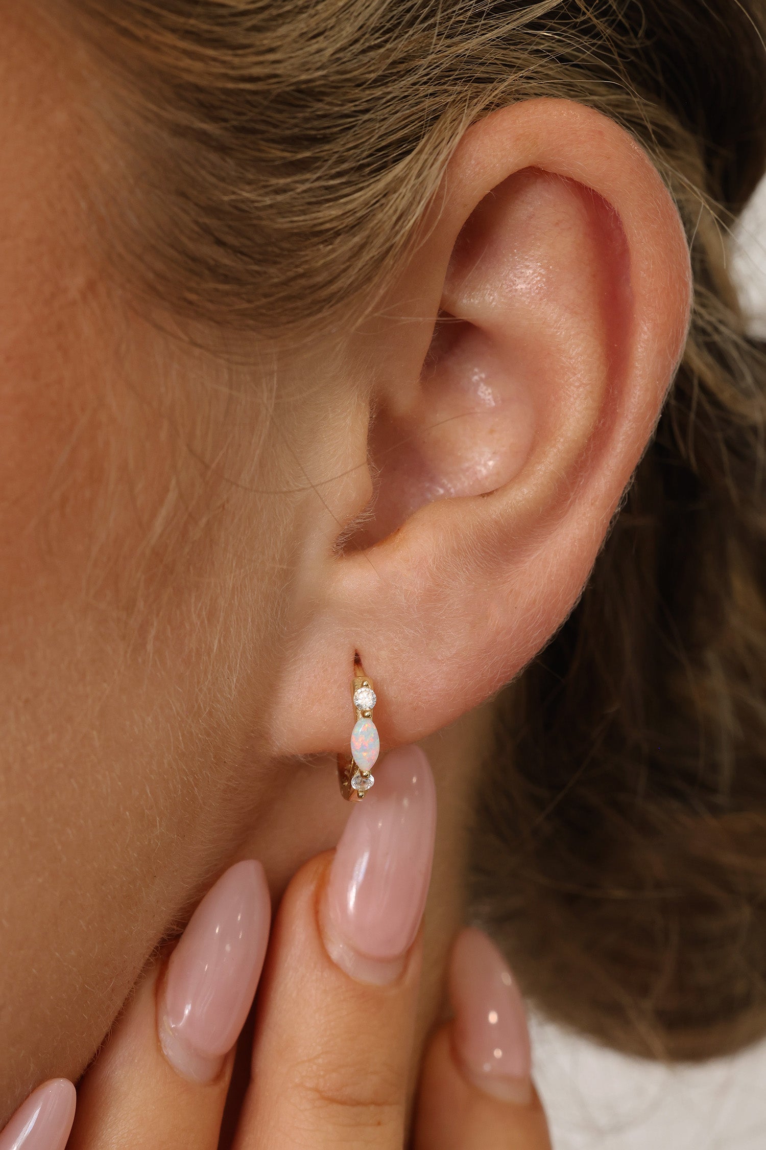 Gold‑plated sterling silver opal huggie hoop earrings with shimmering opal inlays, shown for a soft, elegant, iridescent look.