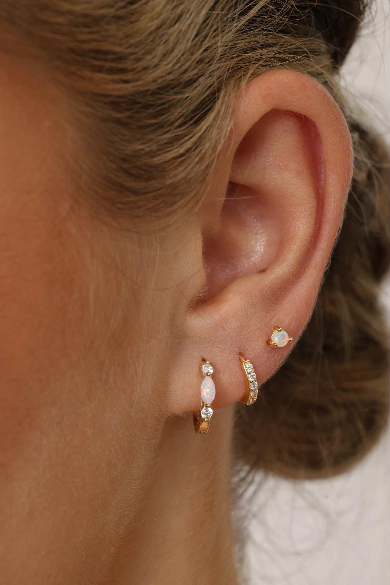 Gold‑plated sterling silver opal huggie hoop earrings with shimmering opal inlays, shown for a soft, elegant, iridescent look.