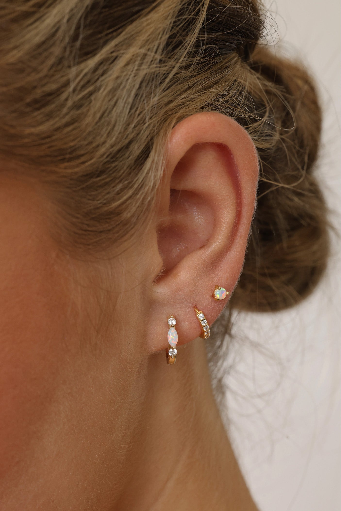 Gold‑plated sterling silver opal huggie hoop earrings with shimmering opal inlays, shown for a soft, elegant, iridescent look.