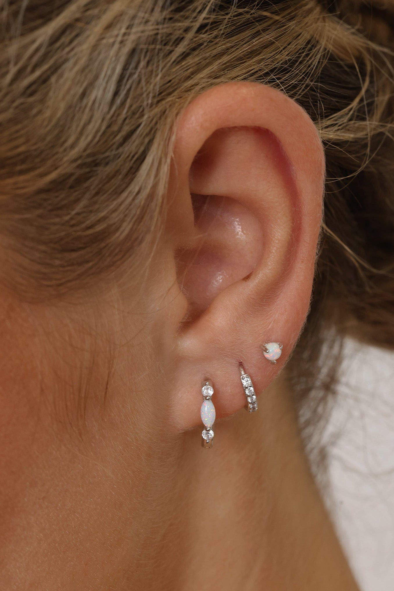 White Gold‑plated sterling silver opal huggie hoop earrings with shimmering opal inlays, shown for a soft, elegant, iridescent look.
