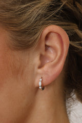 White Gold‑plated sterling silver opal huggie hoop earrings with shimmering opal inlays, shown for a soft, elegant, iridescent look.