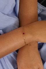 Gold stainless steel birthstone bracelet with a dainty chain and a single bezel‑set gemstone charm hanging at the centre.