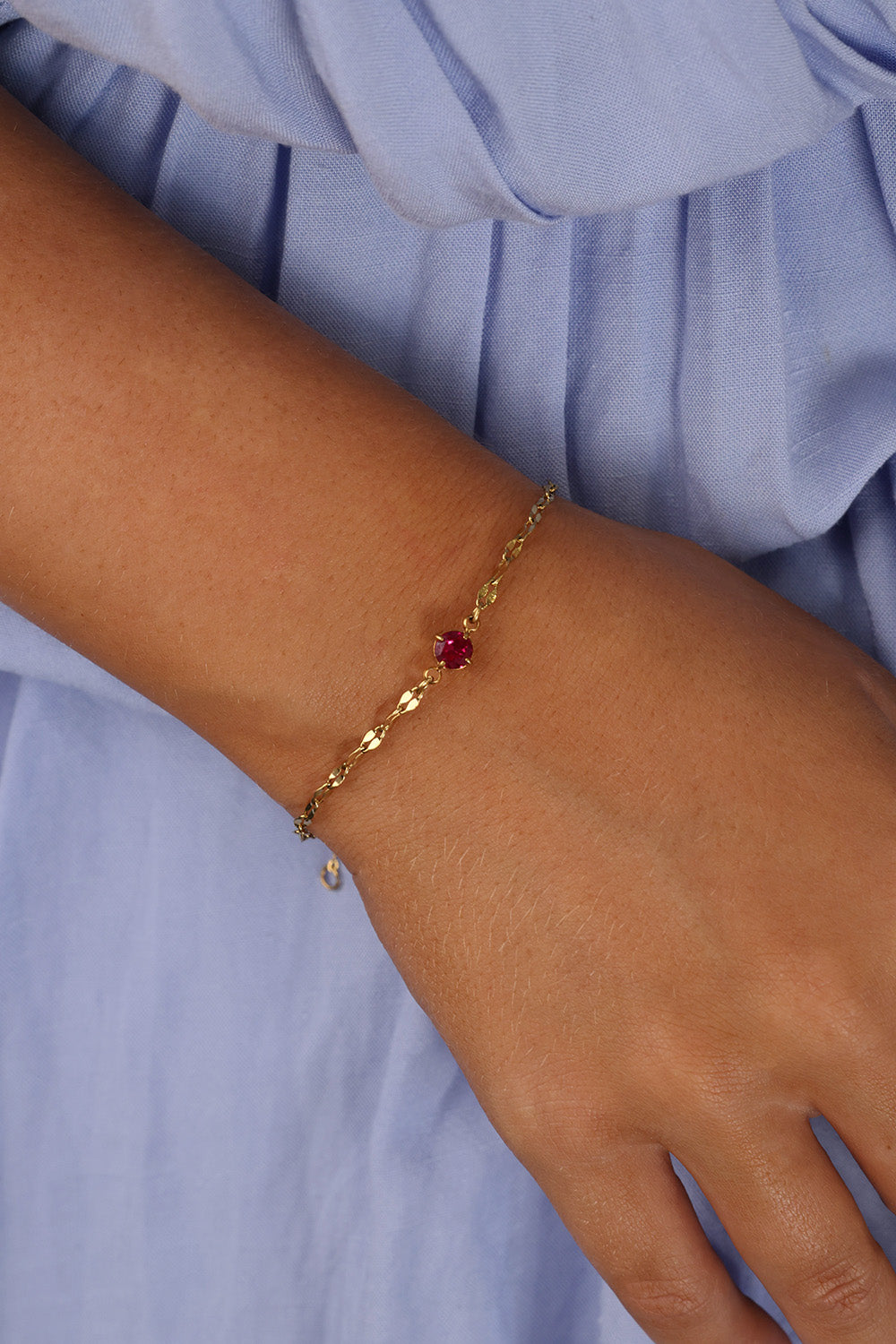 Gold stainless steel birthstone bracelet with a dainty chain and a single bezel‑set gemstone charm hanging at the centre.
