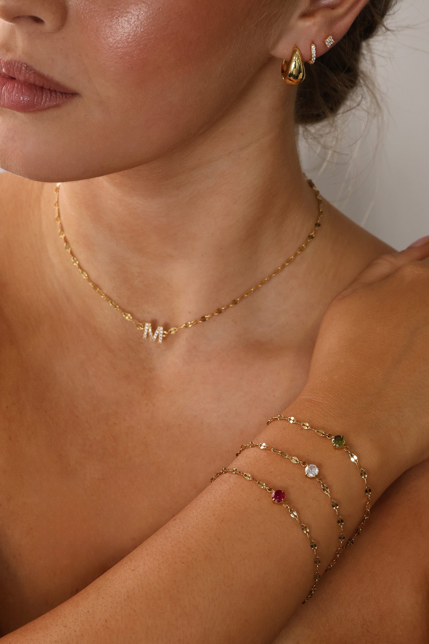 Gold stainless steel birthstone bracelet with a dainty chain and a single bezel‑set gemstone charm hanging at the centre.
