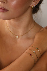 Gold stainless steel birthstone bracelet with a dainty chain and a single bezel‑set gemstone charm hanging at the centre.