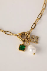 Gold stainless steel necklace with pearl, green birthstone charm, and crystal initial charm on an easy‑open hook.