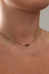 Gold birthstone necklace featuring a delicate chain and a small round gemstone charm.