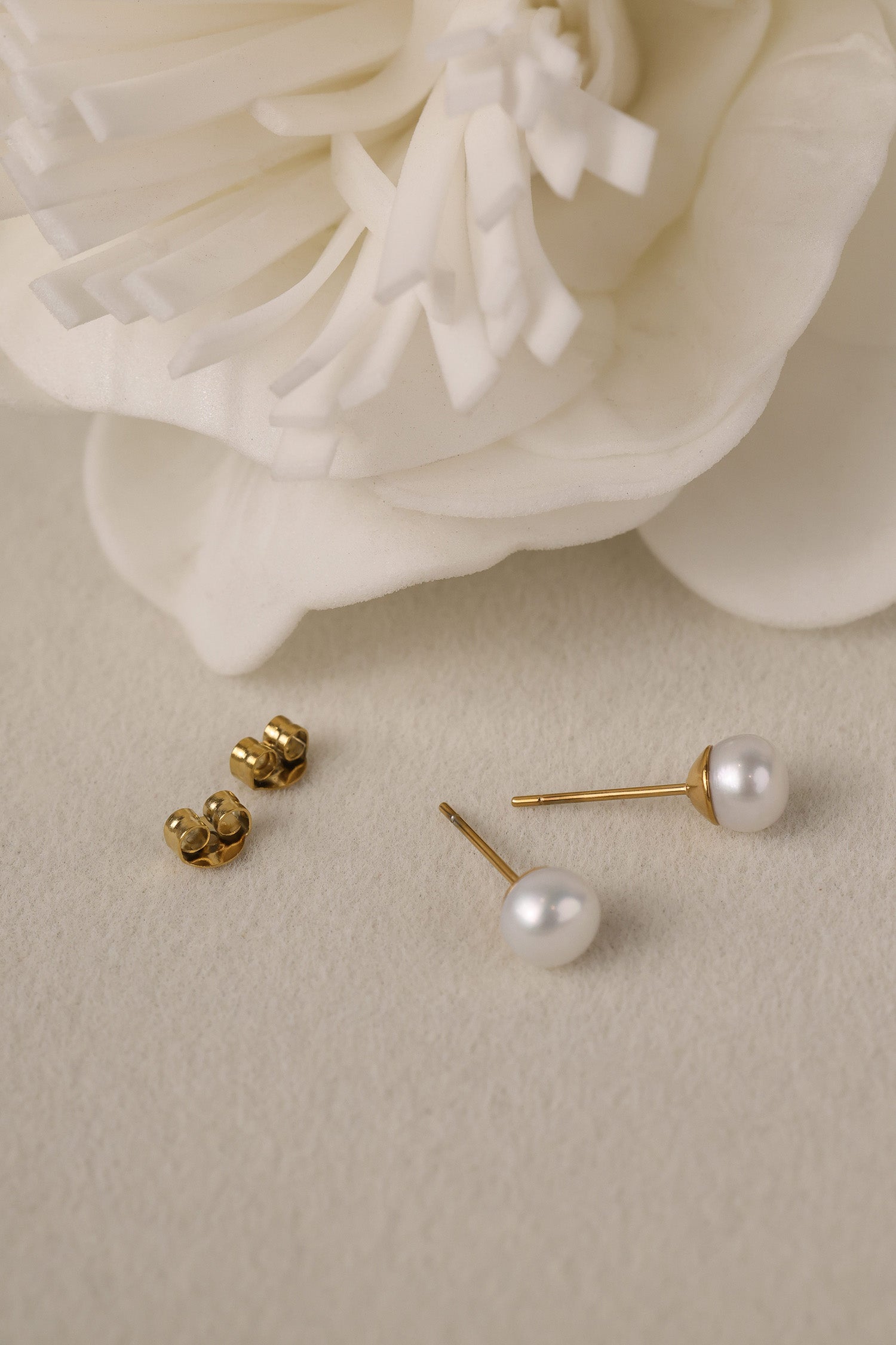 Small freshwater pearl stud earring worn on the earlobe, shown in a gold stainless steel setting.