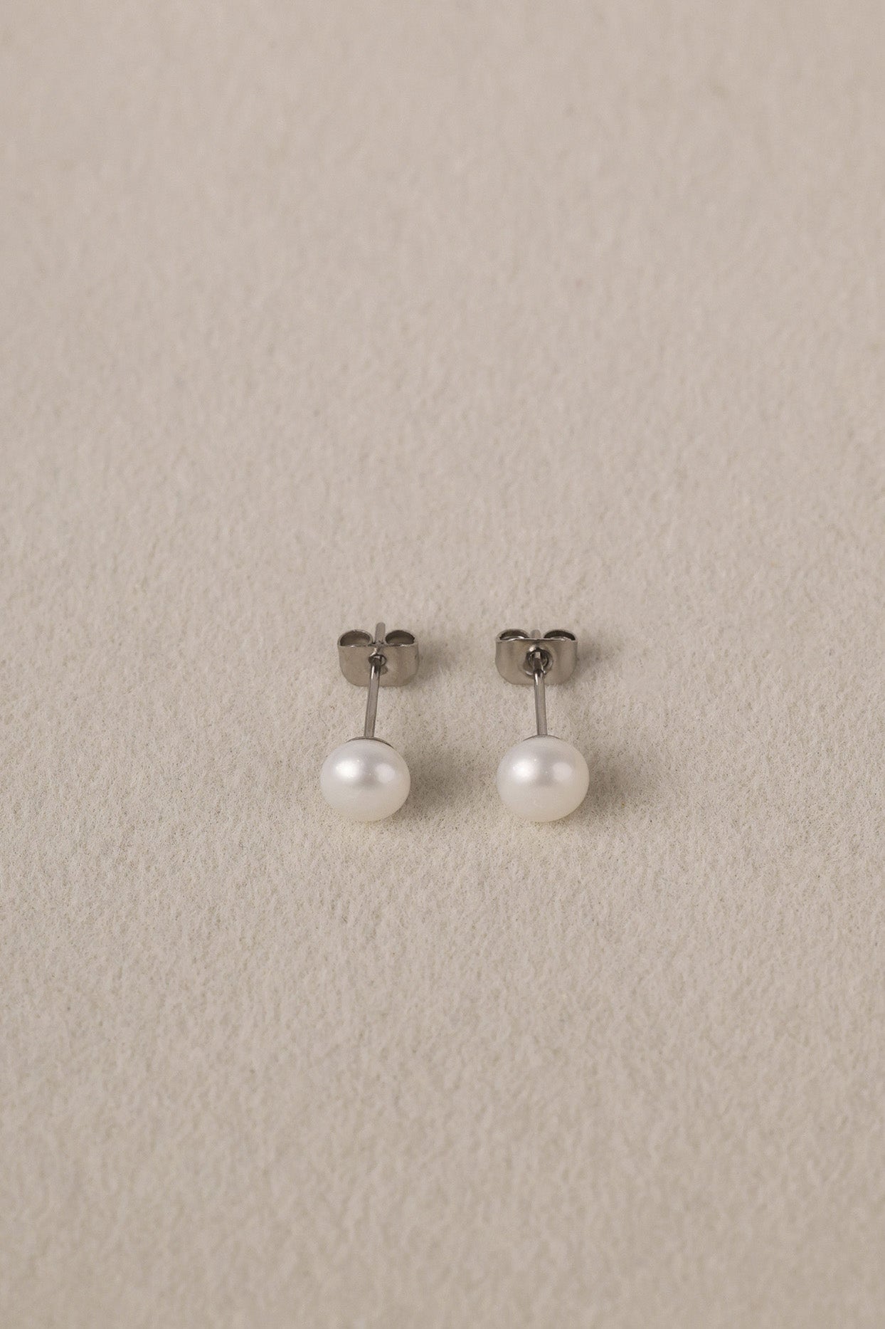 Small freshwater pearl stud earring worn on the earlobe, shown in a gold stainless steel setting.