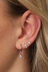 A sterling silver three‑piece earring set featuring a CZ dangle earring, a small CZ huggie, and a delicate teardrop‑shaped stud. Each piece is rhodium‑plated 925 sterling silver with brilliant AAAAA cubic zirconia, designed for a sparkling, elegant look.