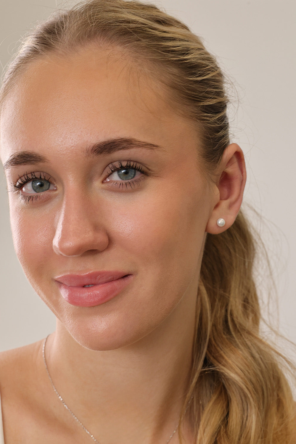 Small freshwater pearl stud earring worn on the earlobe, shown in a gold stainless steel setting.