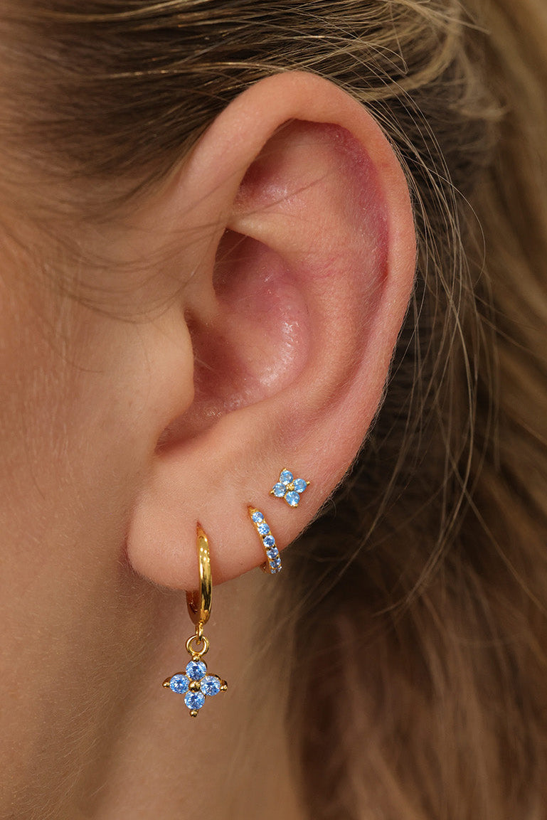 Gold four-leaf clover dangle earrings with blue crystal detailing