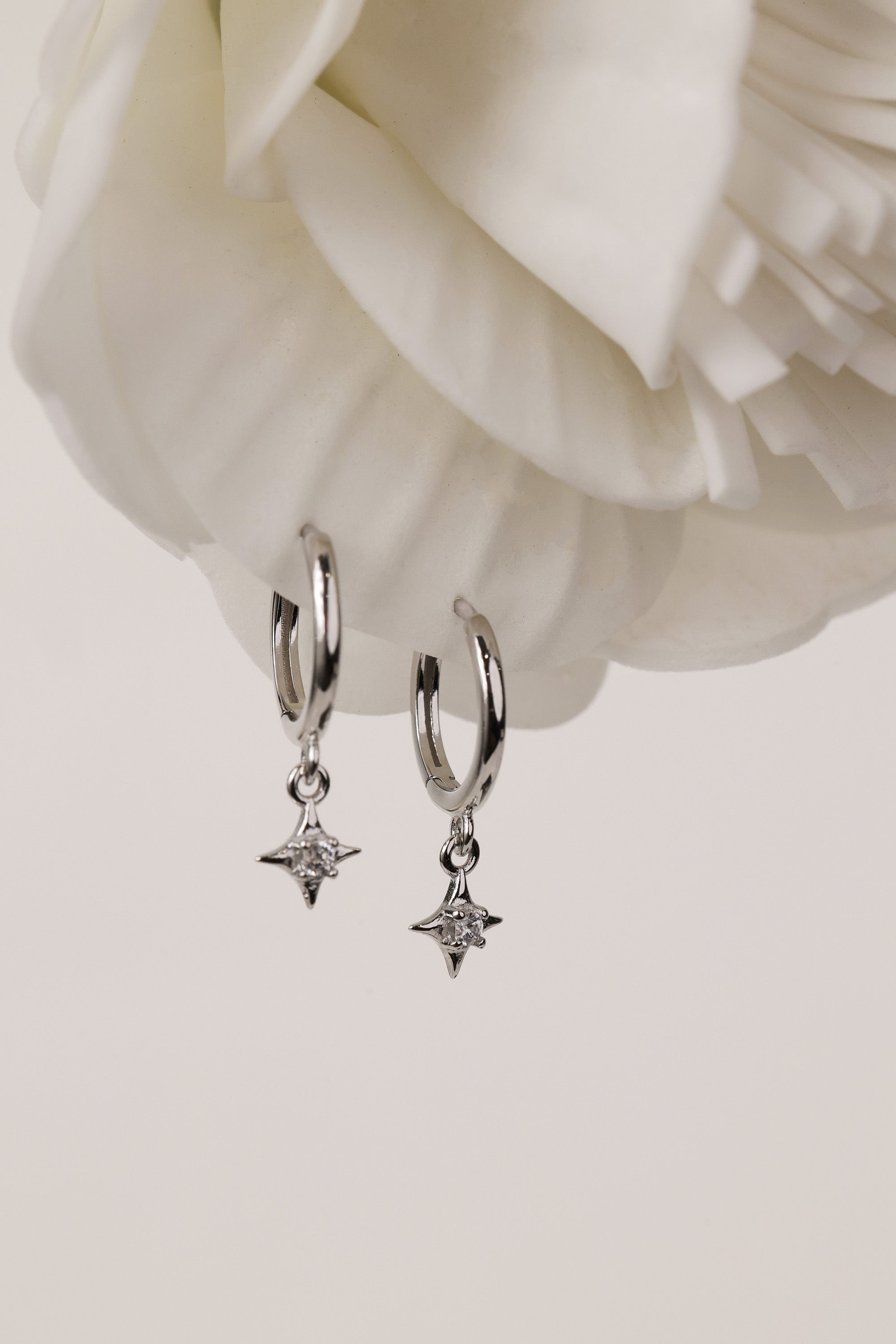 A three‑pair celestial silver earring set featuring a star stud, a moon‑shaped huggie, and a sparkling dangle charm, displayed together for an elegant, versatile look.