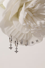 A three‑pair celestial silver earring set featuring a star stud, a moon‑shaped huggie, and a sparkling dangle charm, displayed together for an elegant, versatile look.