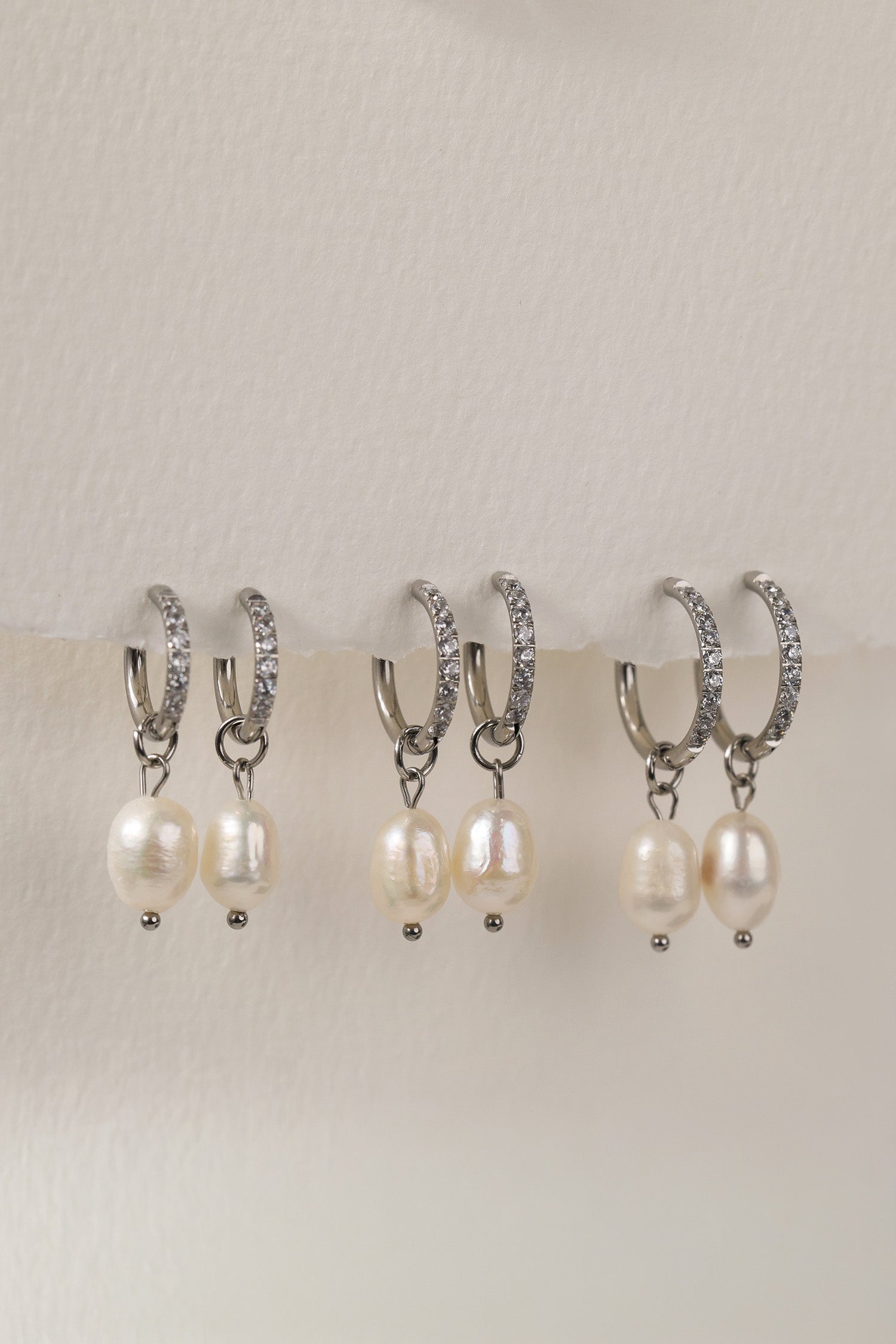 Waterproof pavé hoop earrings with natural freshwater pearl drops. Available in 10mm, 12mm, and 14mm. Tarnish‑resistant, elegant, and perfect for everyday wear.
