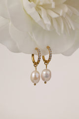 Three sizes of gold pavé waterproof hoop earrings with natural freshwater pearl drops displayed on a textured neutral background