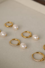 Three sizes of gold pavé waterproof hoop earrings with natural freshwater pearl drops displayed on a textured neutral background