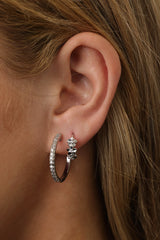 These silver hoop earrings exude elegance and charm, featuring a cluster of delicately crafted flower designs. Each flower is adorned with a sparkling central gemstone, creating a radiant and luxurious effect. Available in Small and Medium.