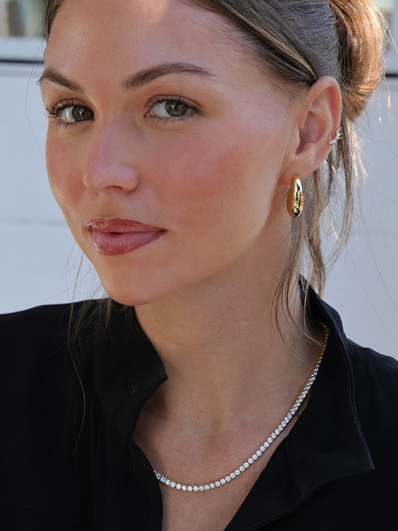 Gold hoop earrings worn with a black collared top, showcasing a minimal and elegant everyday jewellery look.