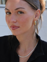 Gold hoop earrings worn with a black collared top, showcasing a minimal and elegant everyday jewellery look.