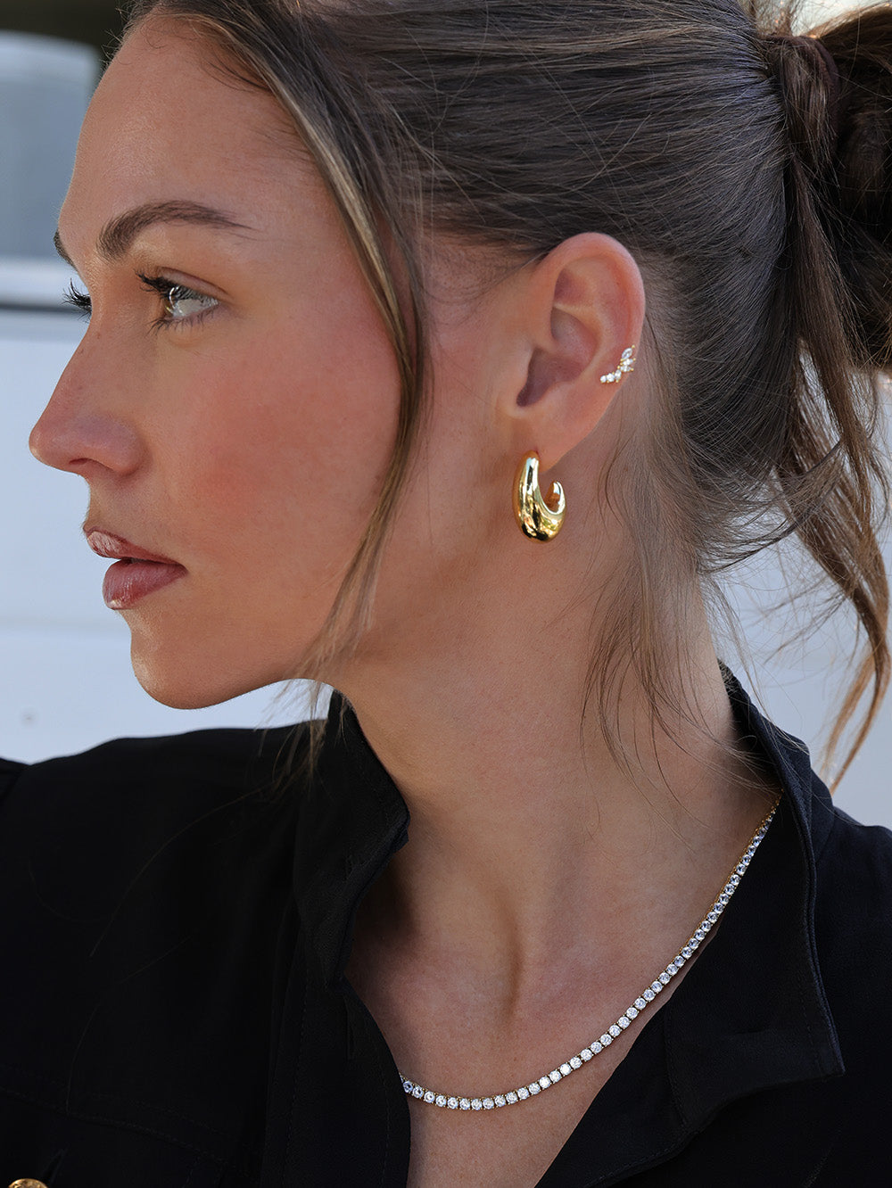 Gold hoop earrings worn with a black collared top, showcasing a minimal and elegant everyday jewellery look.