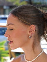 Close-up of a woman wearing earrings with a blurred outdoor background