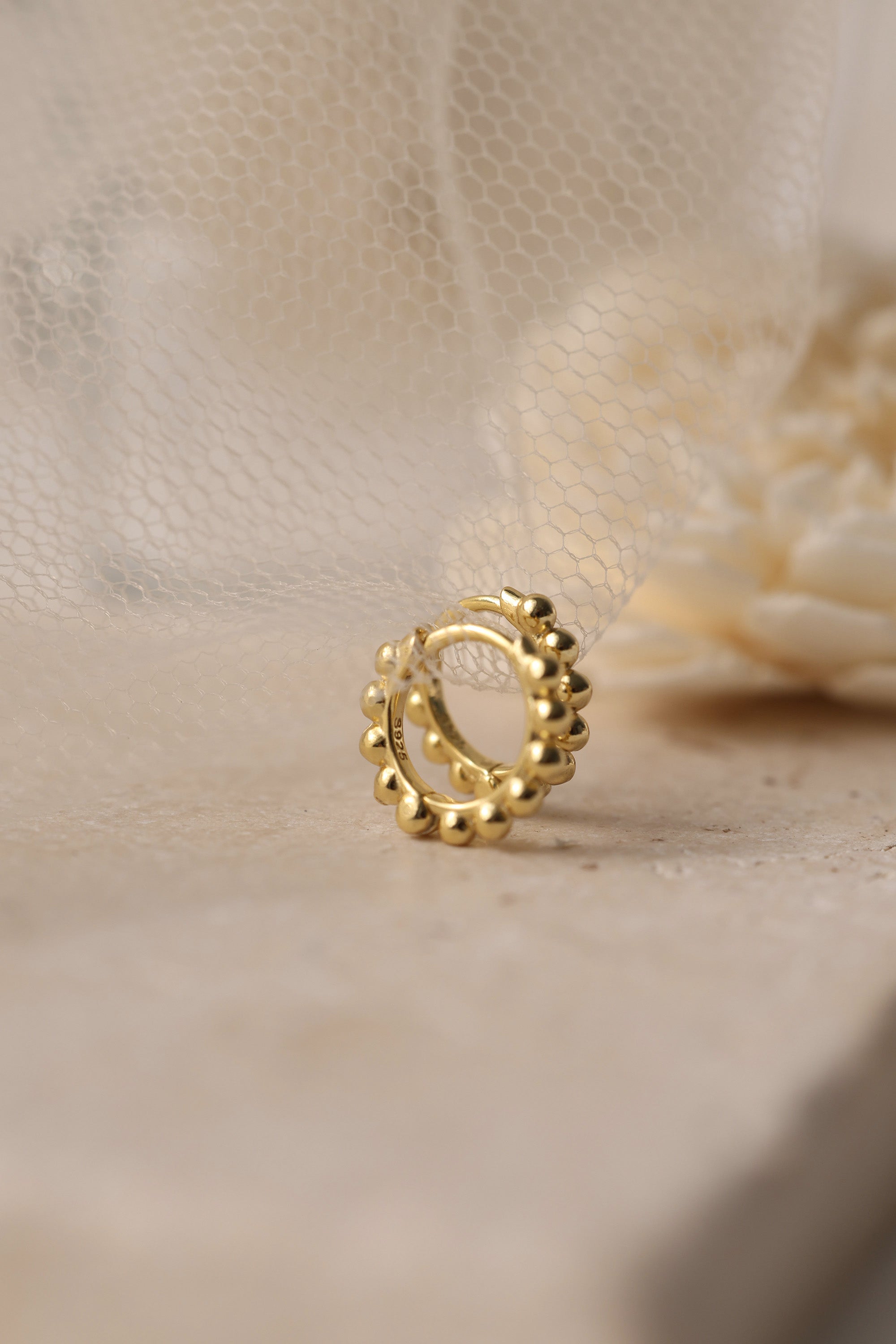 Sterling silver beaded hoop earrings in 8mm and 9mm sizes, featuring polished spherical detailing for a dainty, minimalist look. Displayed on a neutral textured surface with soft floral accents.