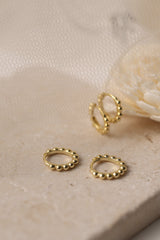 Sterling silver beaded hoop earrings in 8mm and 9mm sizes, featuring polished spherical detailing for a dainty, minimalist look. Displayed on a neutral textured surface with soft floral accents.