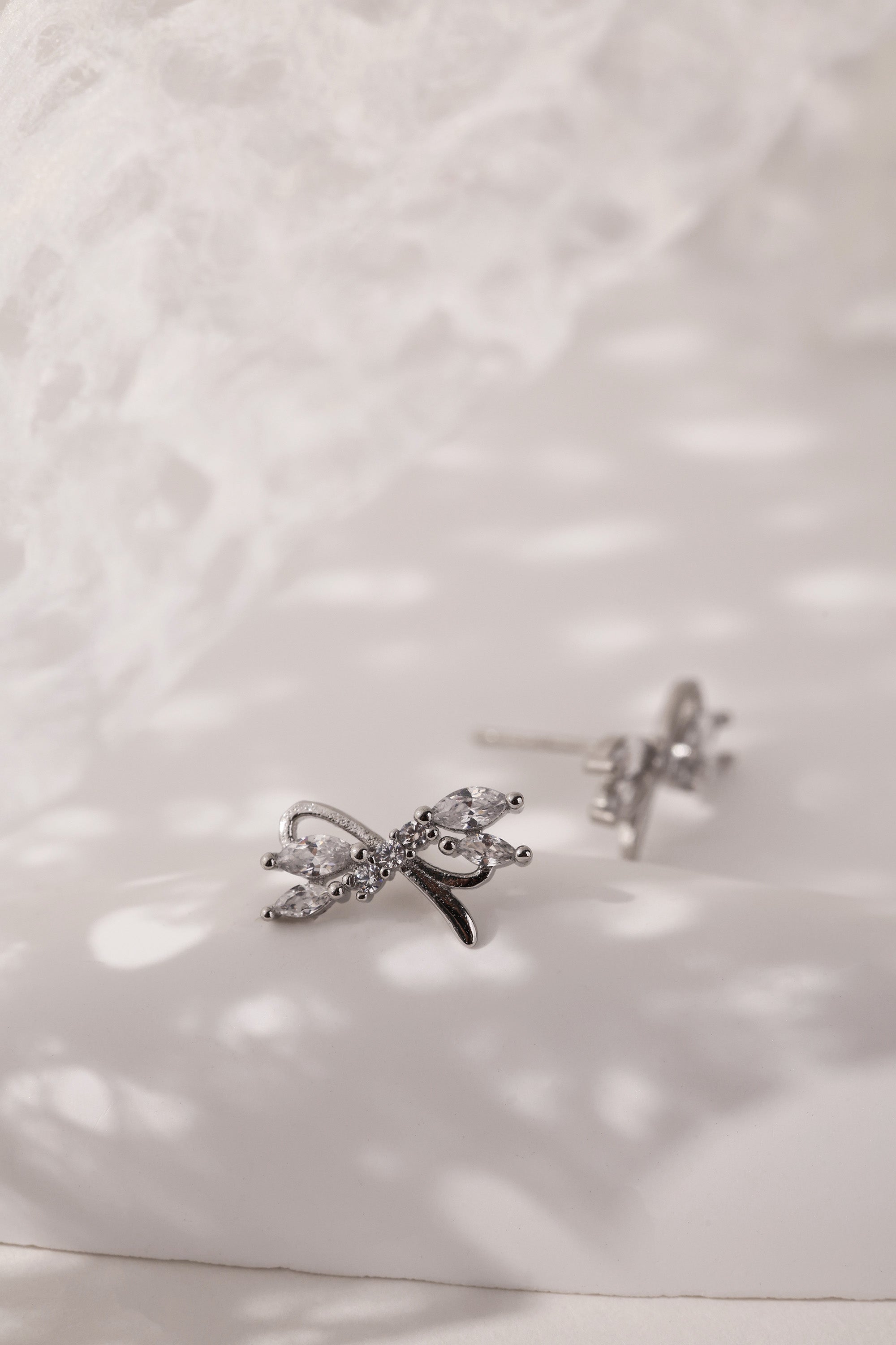 Silver stud earrings with tied ribbon detailing, 13mm wide by 7.5mm high, elegant for daily or special wear