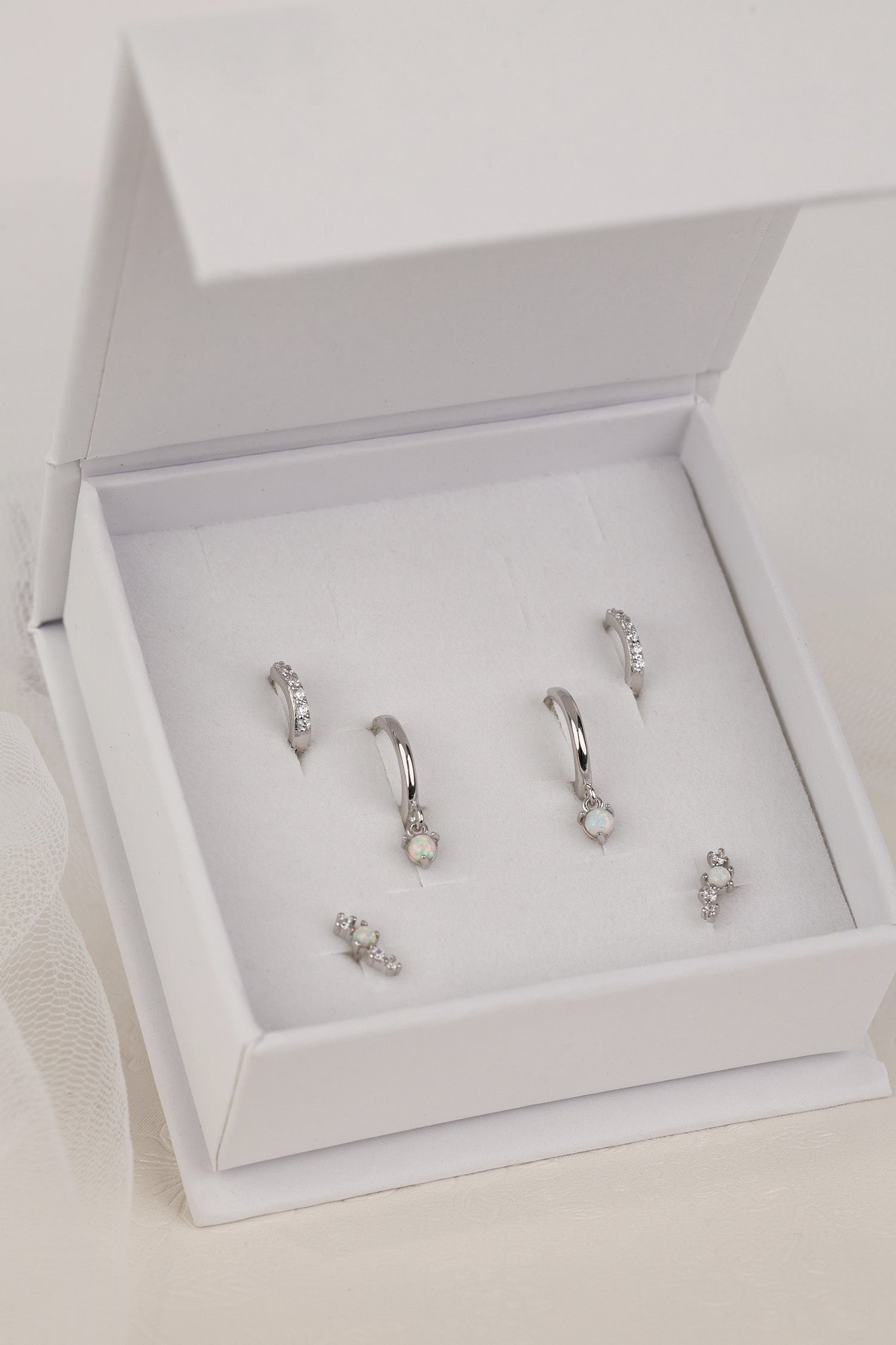 The full silver Dainty Opal set in a white ANETT gift box — opal dangle huggies, pavé huggies and opal studs.